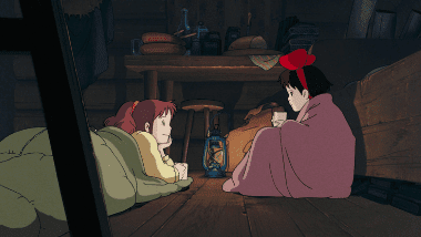 Kiki discussing her worries in front of the fireplace at Ursula's cabin