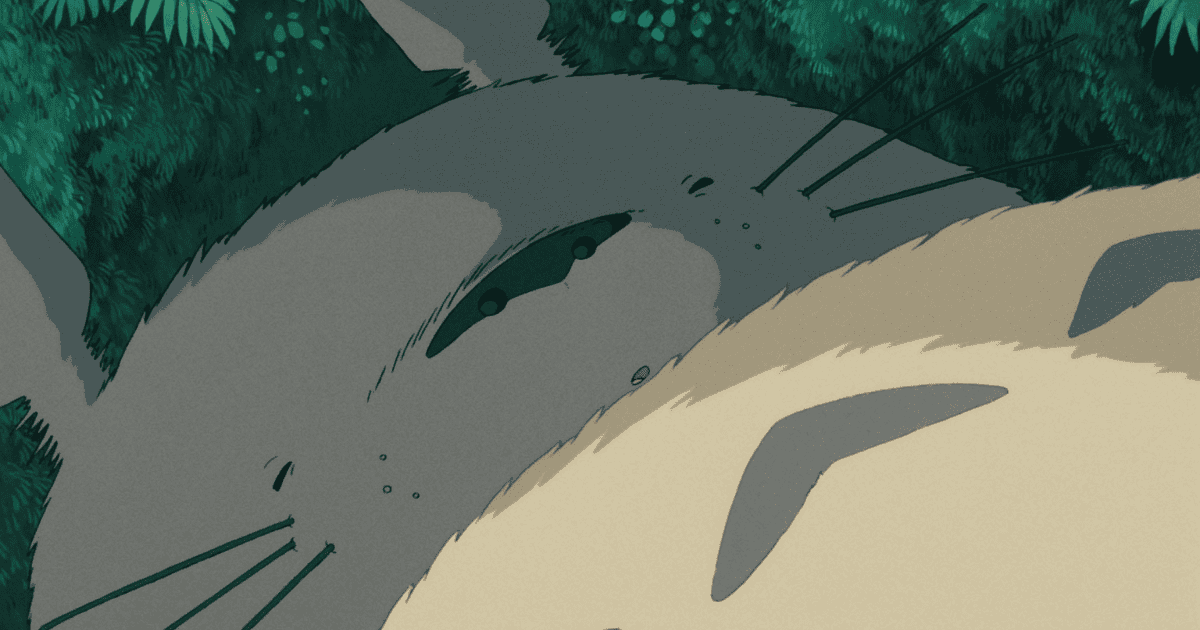 Close-up of Totoro resting peacefully in the forest with soft sunlight filtering through the trees