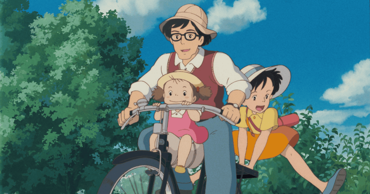 Father riding a bicycle with his two daughters through the countryside under a bright blue summer sky