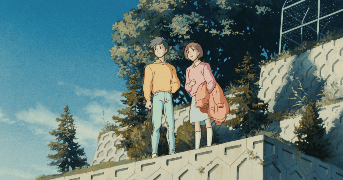 Teenage boy and girl standing together on a hillside path beneath a clear blue sky, surrounded by trees and stone walls